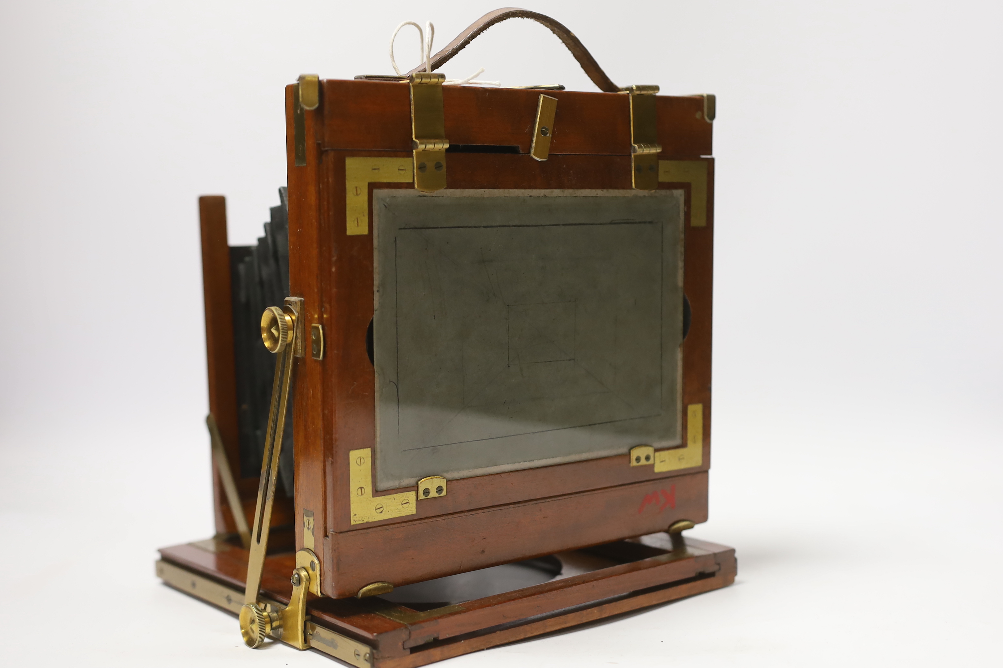 A late nineteenth century brass and mahogany half plate bellows camera with a lens and a shutter action by Thornton Pickard